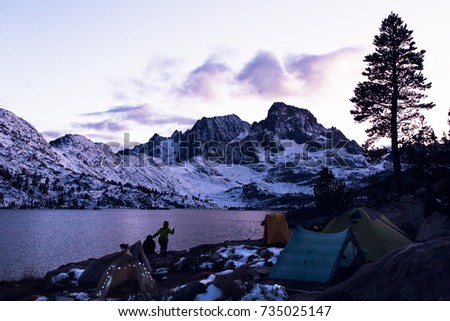 Backpacker and tents on the shore of Garnet Lake at sunset in the Ansel Adams wilderness
