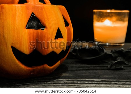 Halloween pumpkin is placed on an old wooden table with candle behind