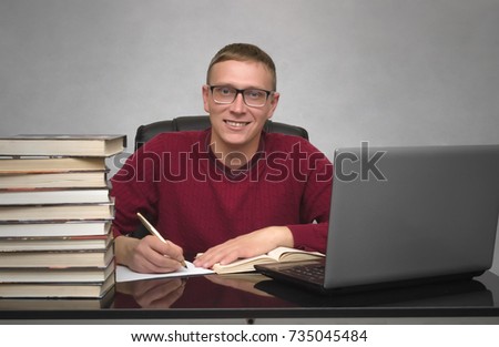 Young happy student man doing homework at the desk table. Young smiling business man signing contract or working with documents.