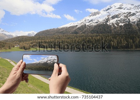 tourist taking picture of alpine landscape at Saint Moritz in Switzerland 