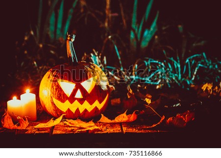 Halloween pumpkin with glowing face on a wooden background in a spooky forest night.