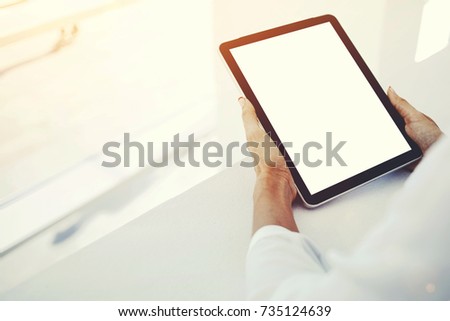 Closeup image of a woman`s hands is holding portable touch pad with mock up blank copy space screen for advertising text message or promotional content.Female is watching news in web on digital tablet