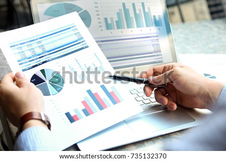 Business man working and analyzing financial figures on a graphs on a laptop outside Royalty-Free Stock Photo #735132370