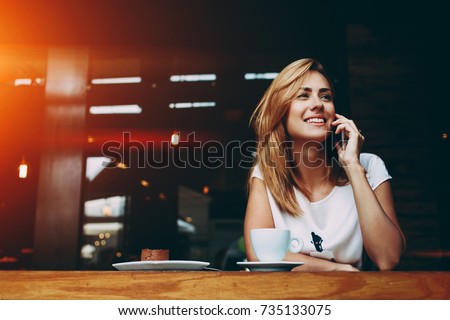 Young charming woman calling with cell telephone while sitting alone in coffee shop during free time, attractive female with cute smile having talking conversation with mobile phone while rest in cafe Royalty-Free Stock Photo #735133075