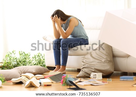 Desperate homeowner complaining after home robbery sitting on a couch of the messy living room at home Royalty-Free Stock Photo #735136507