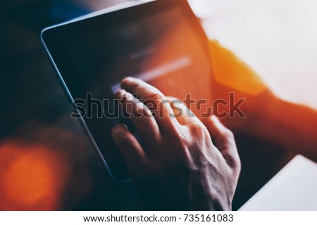 Cropped shot view of a man's hand touching digital tablet screen with copy space for your text message or advertising content, successful male using touch pad for remote work during recreation time