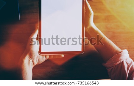 Cropped shot view of man's hands holding touch pad with blank copy space screen for your text message or promotional content, young hipster guy using digital tablet for remote work in modern interior