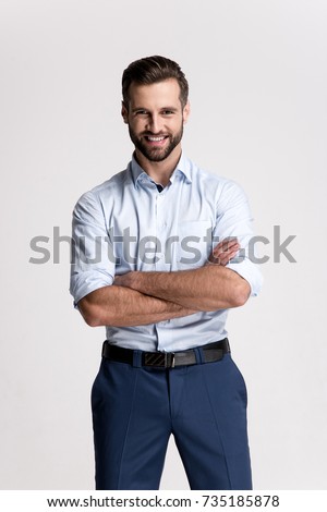 Confident and cheerful. Handsome young man looking at camera with smile while standing against white background.