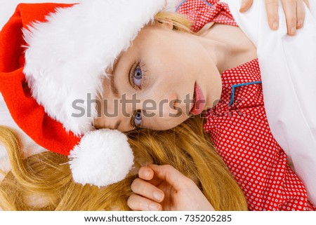 Happy woman waiting for Christmas season wearing pajamas and Santa Claus hat lying in bed.