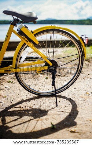 Rear wheel of a yellow bicycle with shadow