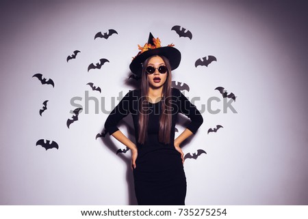 the girl witch scared into the camera. Beautiful girl in a black suit for a party against the background of bats