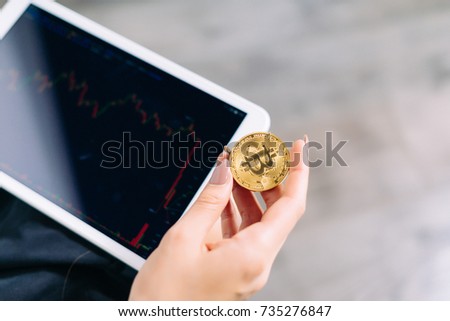 a tablet in the hands of a girl. The girl is holding a gold coin in her hands, a plan of a skull. Crypto currency, bitcoins.