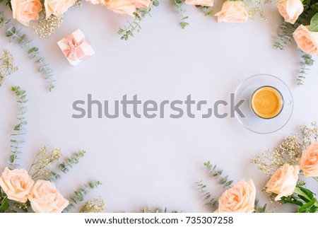 Cup of coffee with gift or present box and flowers on blue background from above, copy space