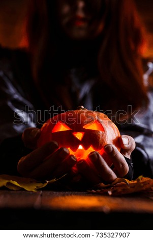 Photo of witch with long hair holding pumpkin on dark background
