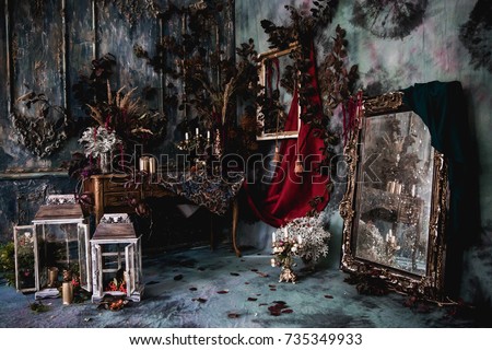 dark decor with dried flowers, vases, chandeliers, textured fabrics against the wall with a golden frame, a wooden table in a luxurious royal Victorian style,candles in old lanterns