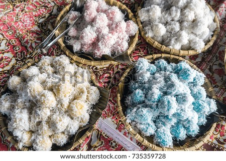 Onde-onde is a traditional rice cake filled with liquid palm sugar and coated in grated coconut on display with signage 'kuih melaka' meaning rice cake with palm sugar