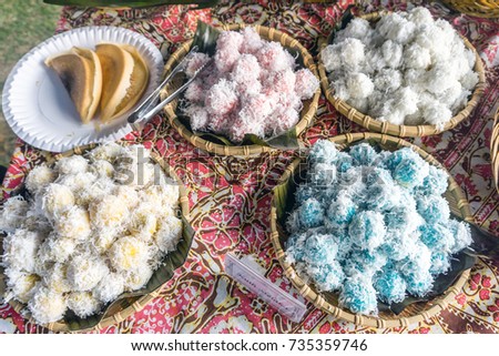 Onde-onde is a traditional rice cake filled with liquid palm sugar and coated in grated coconut on display with signage 'kuih melaka' meaning rice cake with palm sugar