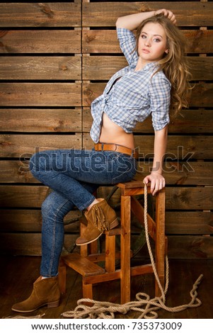 A cowboy style girl sits on a chair on a wooden background