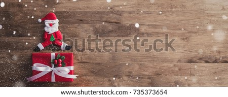 Lovely Christmas holiday top view banner background, creative design idea, with red gift boxes, Santa Claus doll and falling snow effect on wood table
