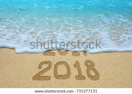 2017 and 2018 written on sandy beach, the wave is covering 2017. New Year 2018 is coming concept. Royalty-Free Stock Photo #735377131