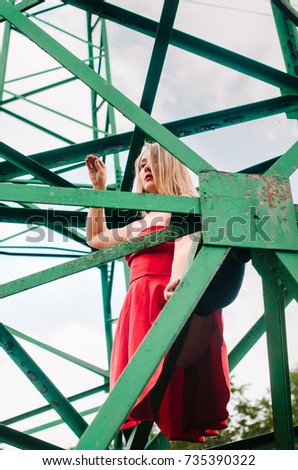 tower grid electricity transmission - high voltage . geometric lines background. girl with strong muscles doing tricks and posing on the height of standing on design .