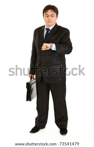 Serious businessman with suitcase looking  at watch isolated on white