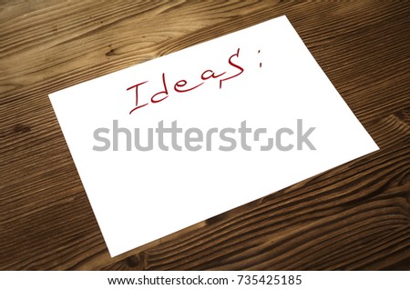 Ideas list paper page on wooden desk table surface with copy space. New ideas concept.