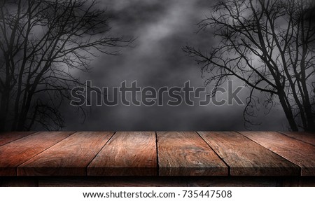 Old wood table and silhouette dead tree at night for Halloween background. Royalty-Free Stock Photo #735447508