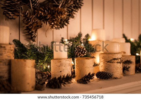 Christmas decor. Fireplace decorated with birch sprees, candles, cones and spruce branches
