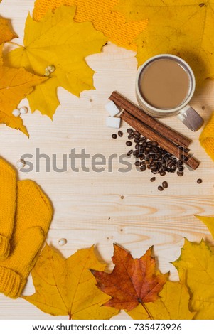 autumn composition on wooden table orange and yellow leaves, mittens, scarf, Cup, coffee beans and cinnamon, white sugar