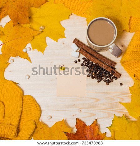 autumn composition - sticker on wooden table orange and yellow maple leaves, mittens, scarf, Cup, coffee beans and cinnamon