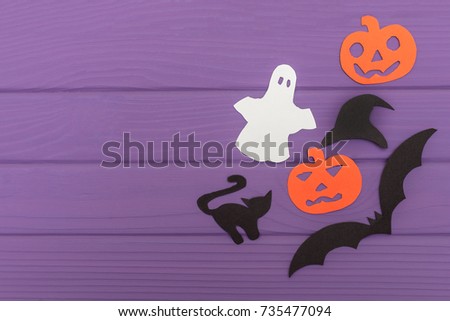 Halloween silhouettes cut out of paper made of corner frame with pumpkins, bat, cat, ghost, hat on purple board. Halloween holiday. Copy space