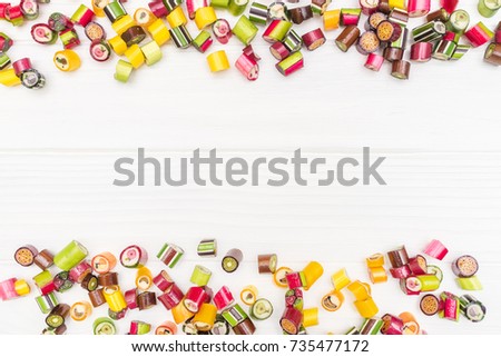 A frame made of colored caramel candies on white wooden background. Copy space