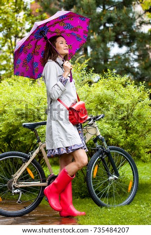 fashion. style. beautiful woman in an autumn rainy garden with an umbrella near a bicycle