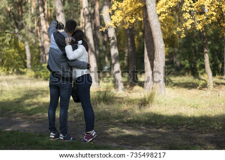 A loving young couple doing selfie in the park. Back view.