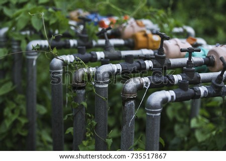 Closeup. Row of pipelines and water meters are located in the bushes.
