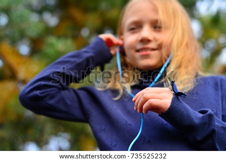 girl in headphones with phone in the forest with her hair down
