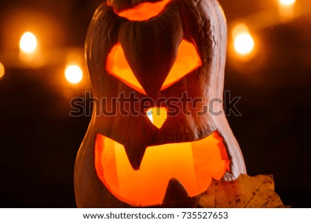 Photo of halloween pumpkin cut in shape of face on background with burning yellow lights