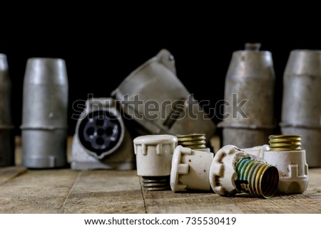 Old plug and socket high voltage. Old electrical accessories. Wooden table, black background