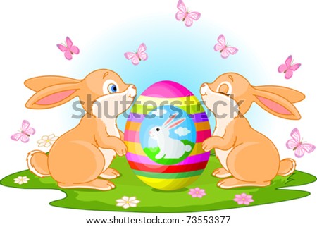 Two cute rabbits holds Easter Egg on the spring meadow