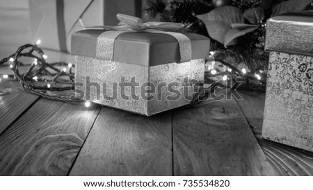 Black and white image of gifts in boxes on wooden floor under Christmas tree