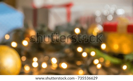 Blurred image of glowing Christmas lights, baubles and gifts