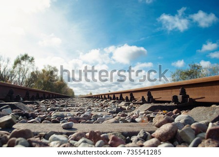 Sleepers and stones between rails under the blue sky, closeup shot