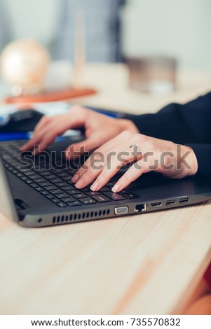 women's hands are typing on the laptop's keyboard.