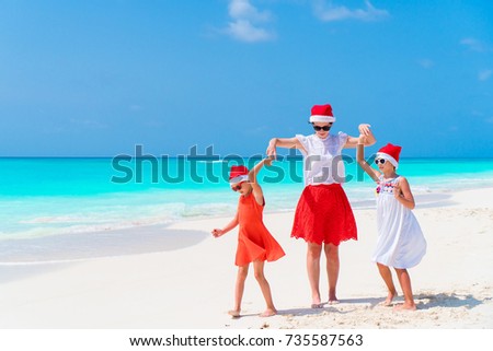 Happy beautiful family in red Santa hats on a tropical beach celebrating Christmas