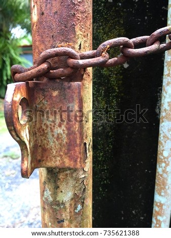 An old rusty gate with a chain of a green place.