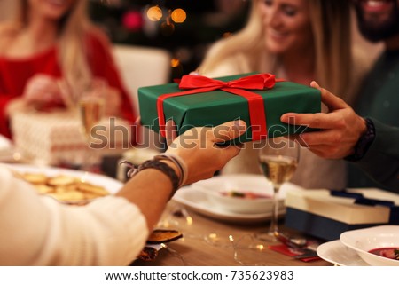 Group of friends giving Christmas presents at home