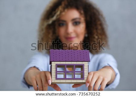 Beautiful black woman portrait. Holds a miniature toy doll house