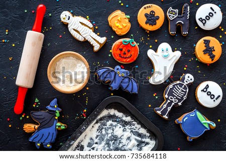 Cook halloween gingerbread cookies bat, skeleton, ghost. Sweets near rolling pin and baking sheet. black background top view
