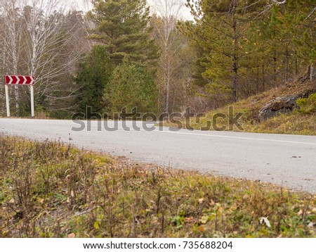 autumn mountains road with sharp turn sign